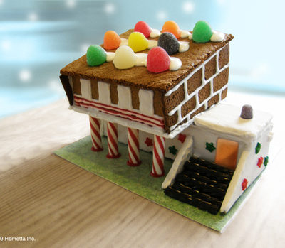 A gingerbread candy house sits on a wooden table.