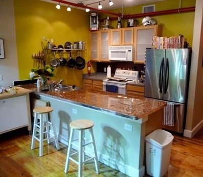 A kitchen with a pastel light green counter side with two stools in front of it.