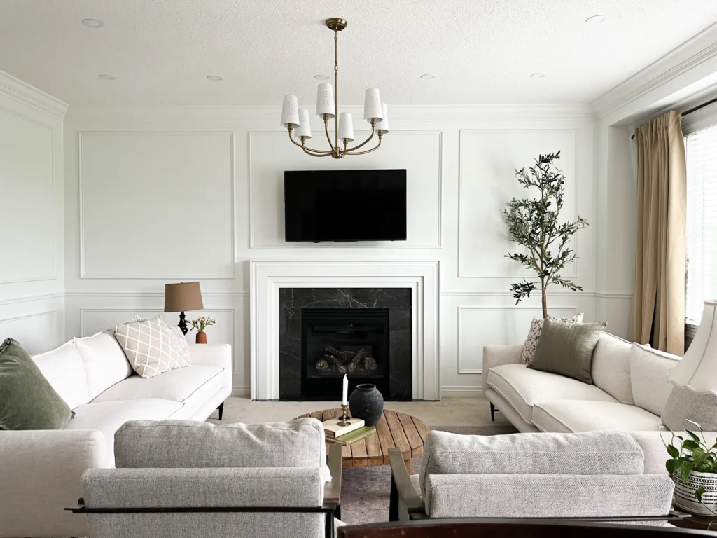 Cream walls in living room with tv and fireplace on wall and white baseboard and crown molding wainscoting