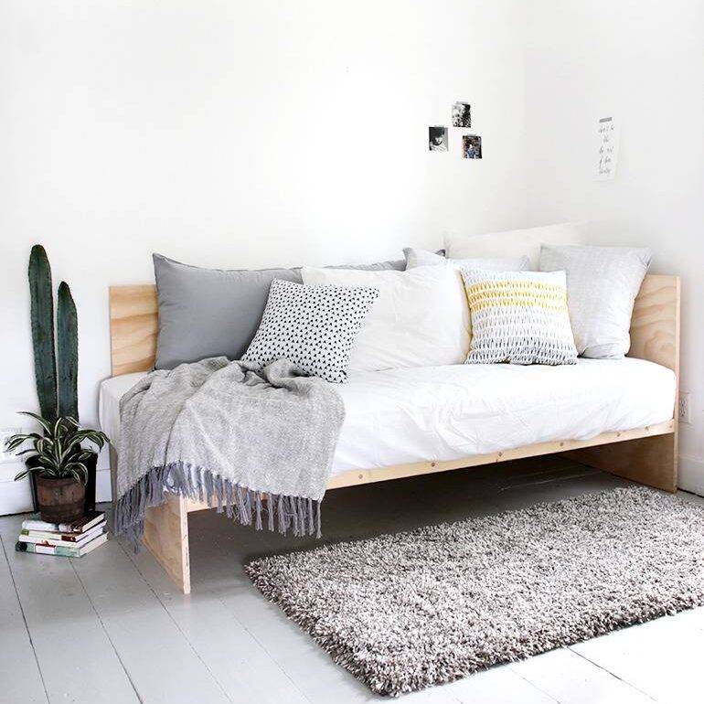 Daybed filled with pillows in the corner of a white and grey room.