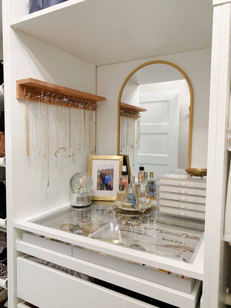 IKEA closet unit with jewelry on top of clear drawer with jewelry hanging