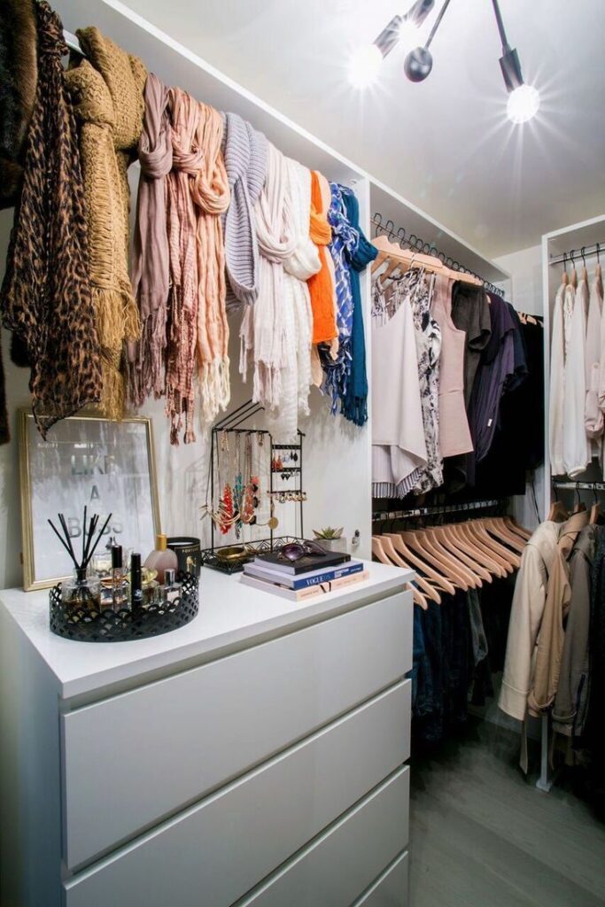 White closet with shelf and hanging scarfs 