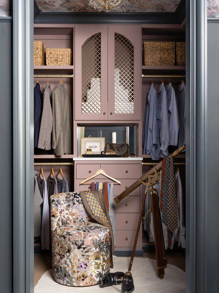 Painted drawers in dusty pink in closet with decorative lounge chair in front.