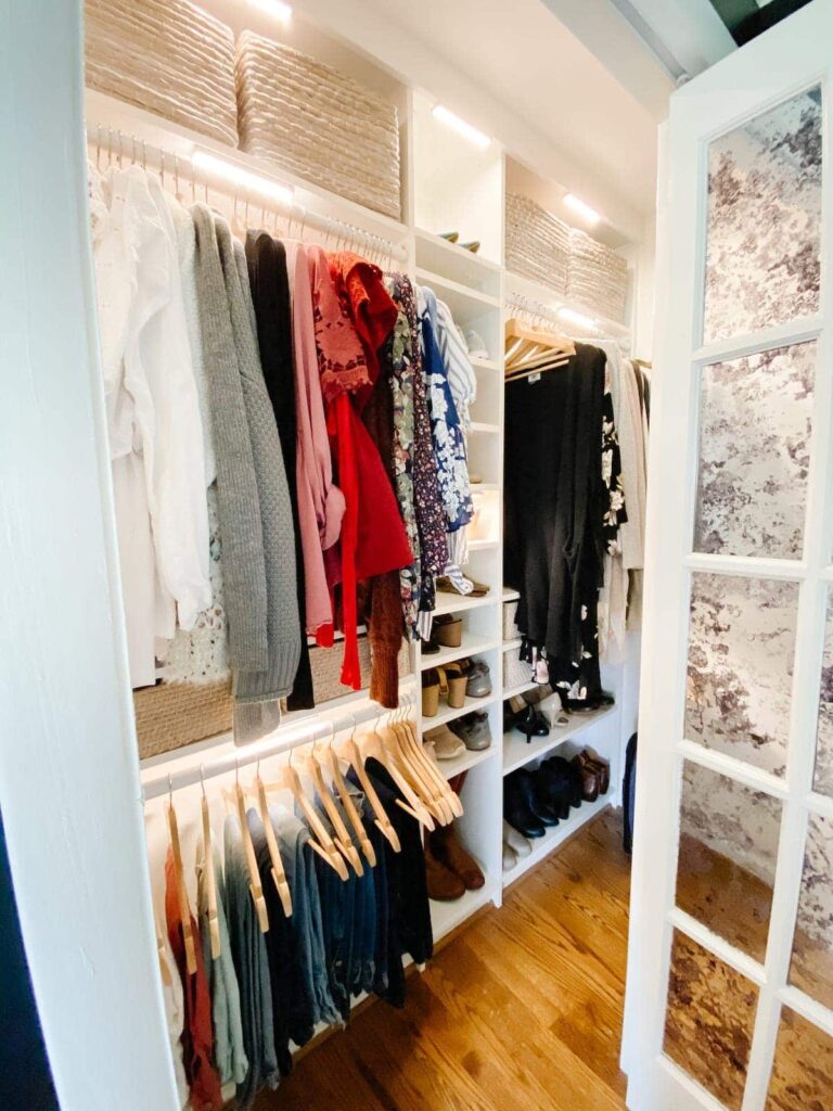 White closet with racks of clothes and LED lighting inside 