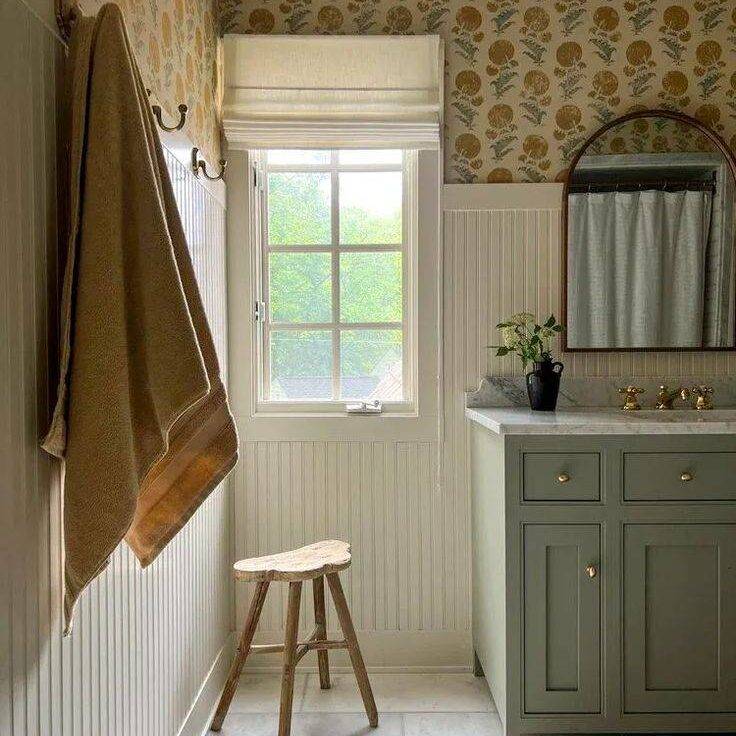 Cream colored bathroom with sage green sink and vertical wainscoting