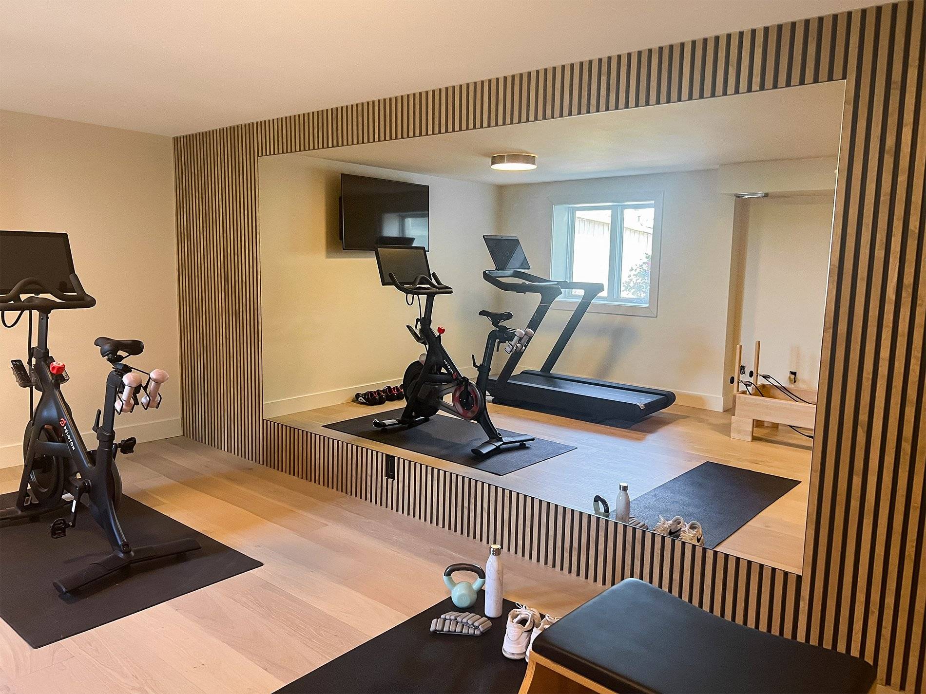 Basement gym with treadmill and elliptical machine on hardwood floor