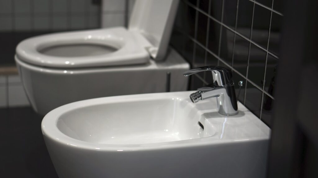 A white bidet toilet sitting next to a white sink