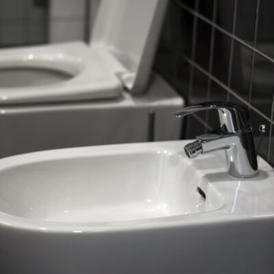 A white bidet toilet sitting next to a white sink